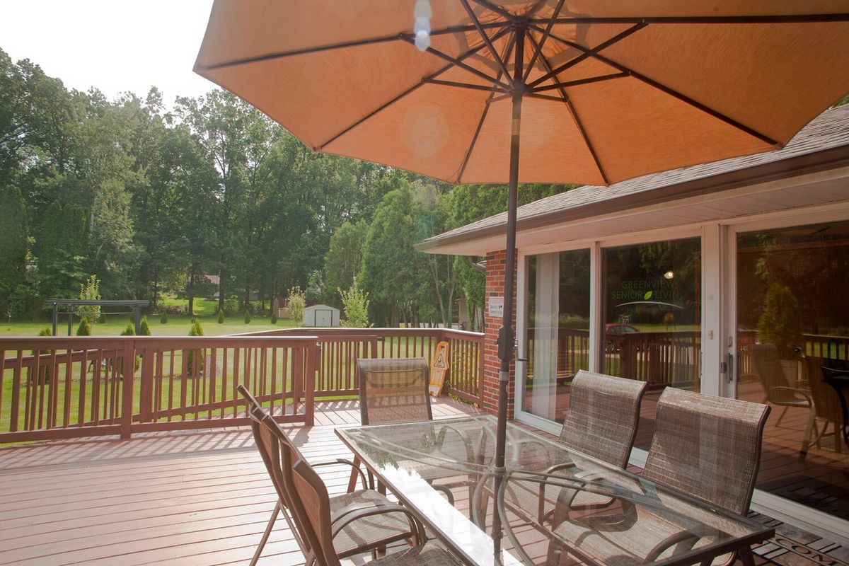 A cozy backyard patio with a table, chairs, and an umbrella providing shade.