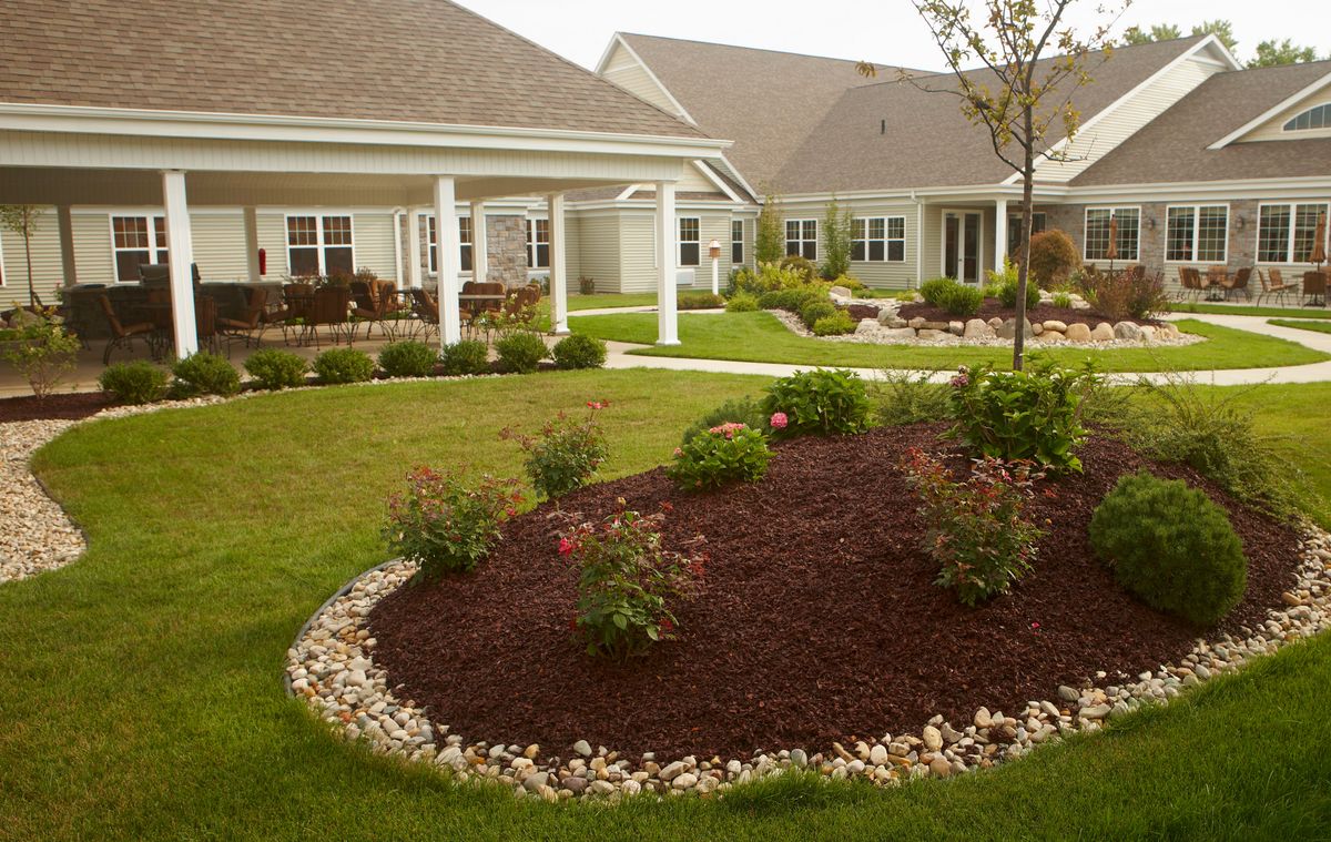 A beautifully landscaped garden with a pathway and mulched shrub area in front of residential houses.
