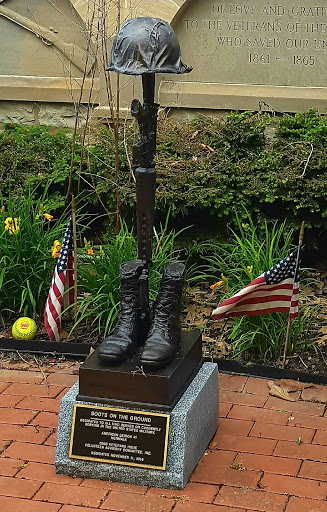 A tribute to military service featuring a statue of boots and a flag, symbolizing honor and remembrance.