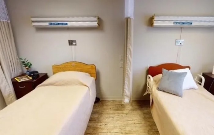 A hospital room with two single beds and privacy curtain.