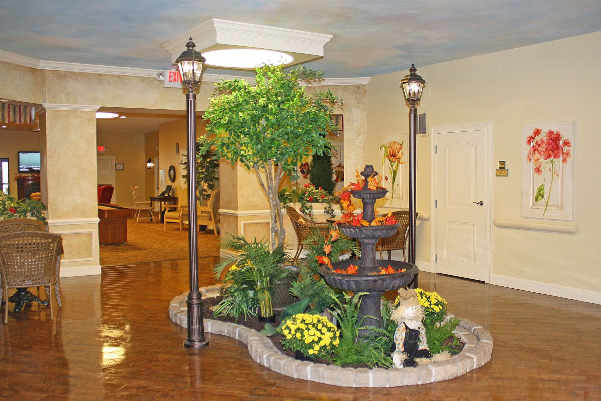 A beautifully decorated indoor garden with a fountain and lampposts in a lobby setting.