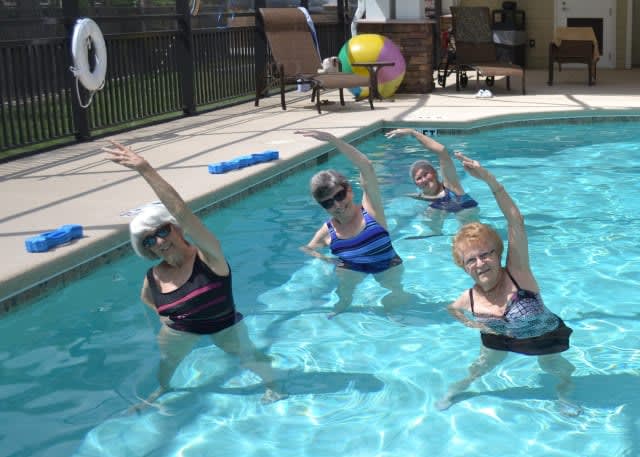 A group of people performing water aerobics in a pool.