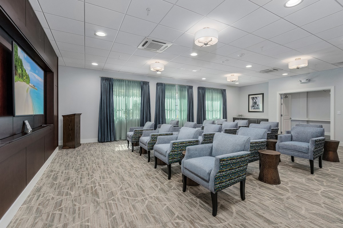 A modern meeting room with rows of chairs, a podium, and elegant lighting.