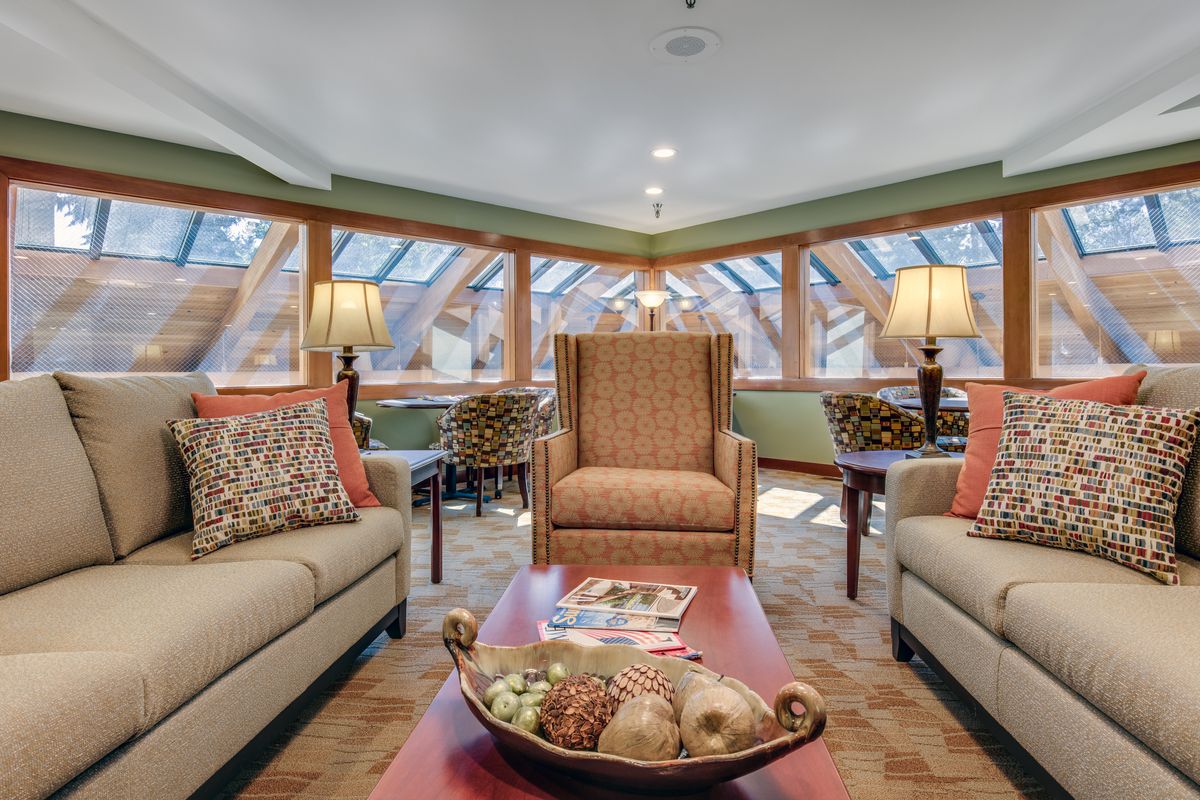 A cozy living room featuring large windows, comfortable sofas, and warm lighting.