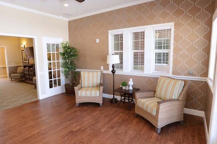 Cozy living room with armchairs, a lamp, and a potted plant.