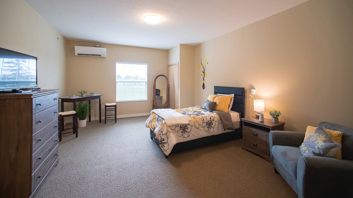 A cozy bedroom interior with a single bed, bedside table lamp, and window.