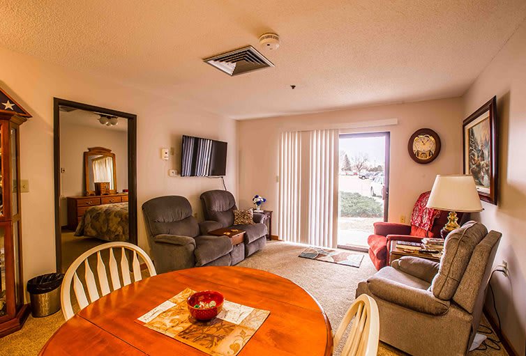 A cozy living room with a dining area, featuring comfortable sofas, a TV, and a wooden dining table.