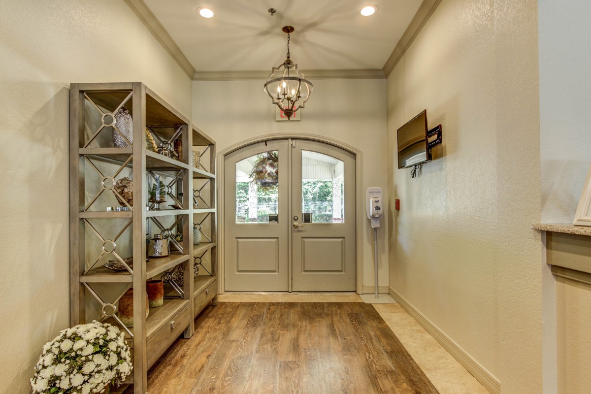 A beautifully decorated entryway featuring a chandelier, shelves with decor, and double doors.
