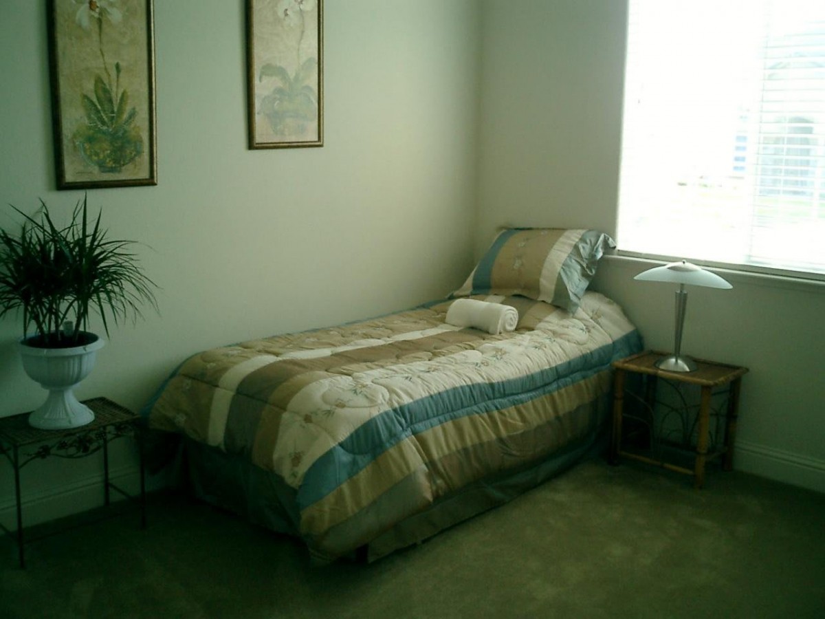 A simple and tidy bedroom with a single bed, side table, and lamp.