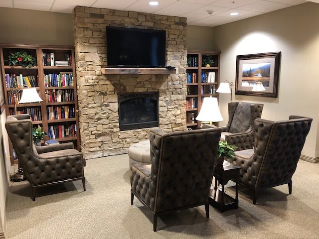 A cozy living room with a stone fireplace, bookshelves, and comfortable seating.