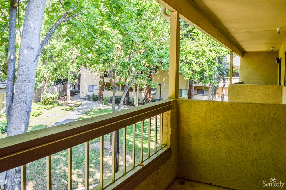 A view from a balcony overlooking an apartment complex surrounded by trees.