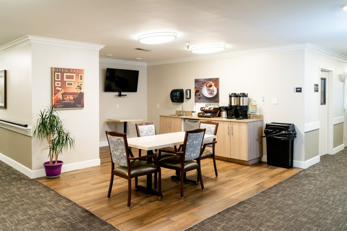 A cozy dining area with a table and chairs, featuring a coffee station and a television mounted on the wall.