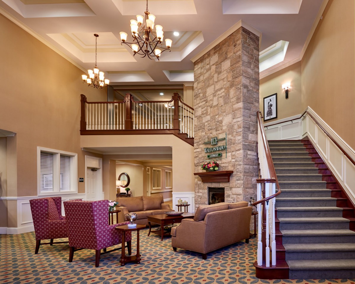 A spacious lobby with comfortable seating, a grand staircase, and an elegant chandelier.