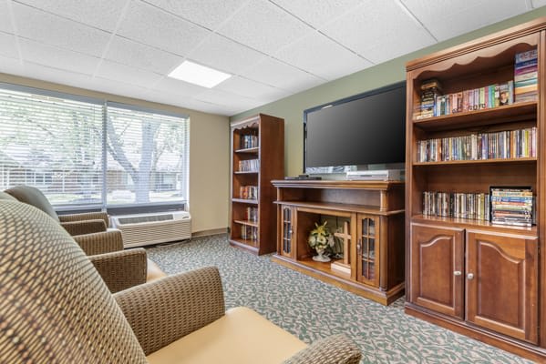 Cozy living room with a large TV, bookshelves, and comfortable seating.