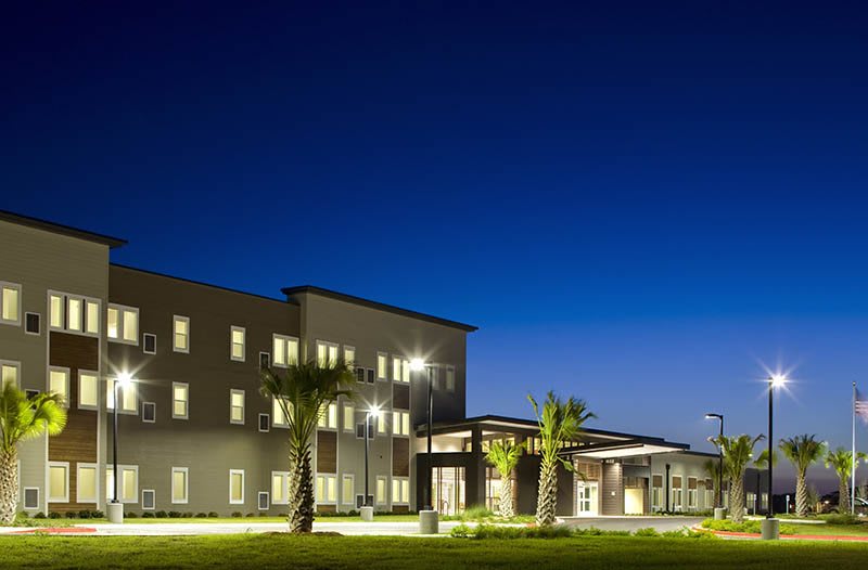 A well-lit building with palm trees at night.