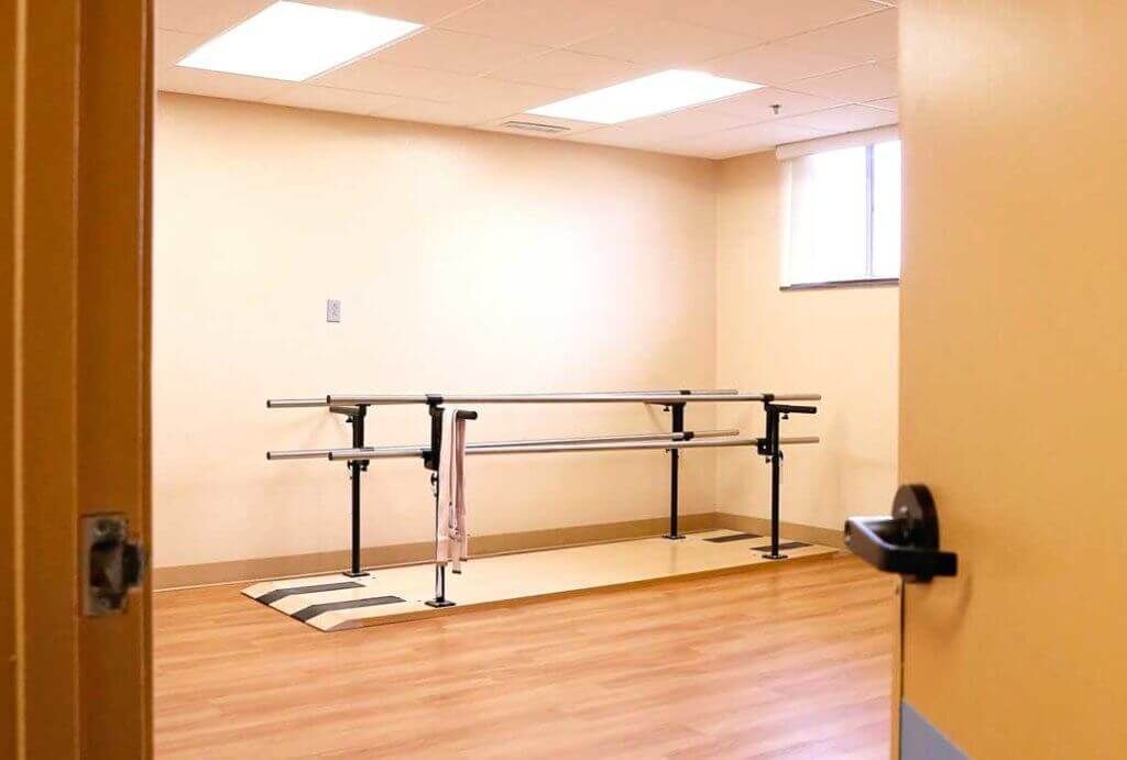 A physical therapy room equipped with parallel bars for rehabilitation exercises.