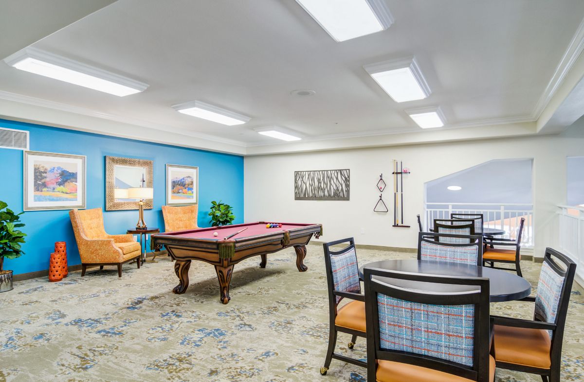 A spacious game room featuring a pool table, comfortable seating, and wall artwork.