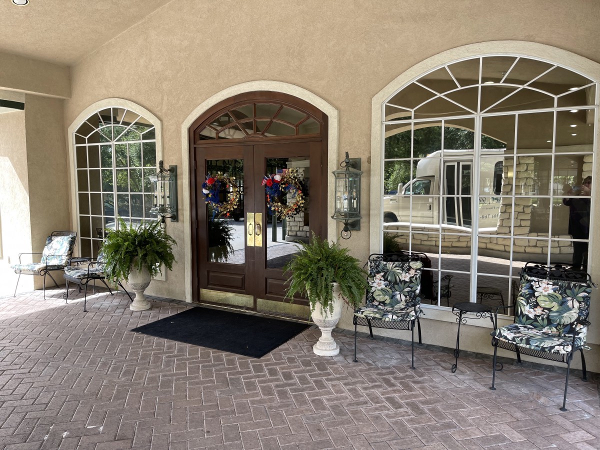 A welcoming building entrance with large windows, decorative plants, and seating.