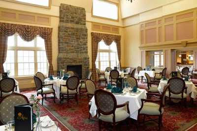 Elegant dining room with a large stone fireplace and set tables.