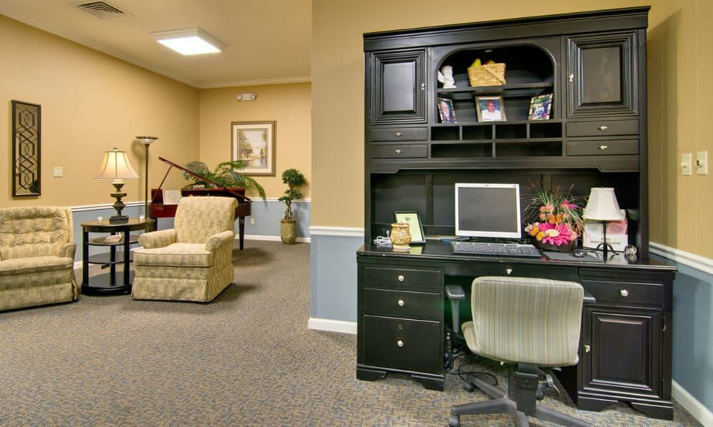 An office space with a desk and computer set up, adjacent to a lounge area with comfortable seating.