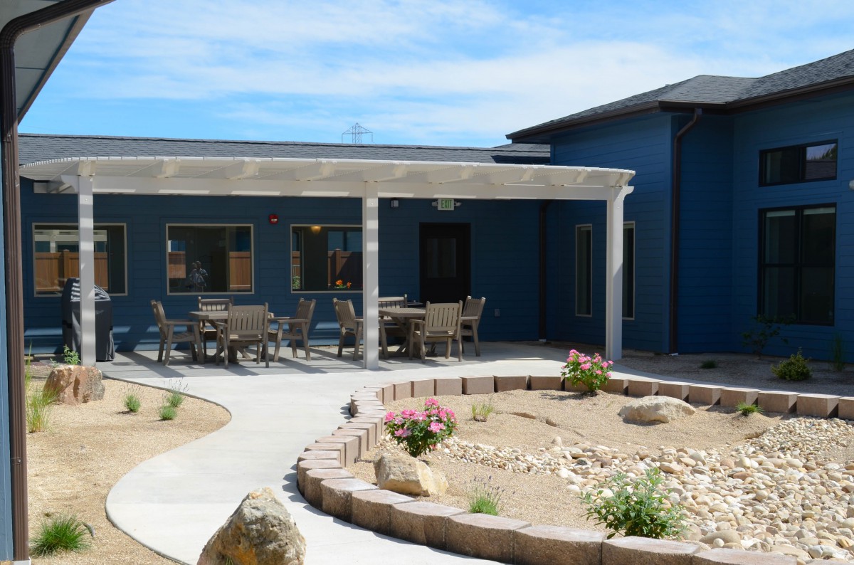 A modern building with an outdoor patio and desert landscaping.