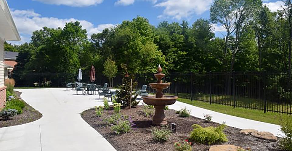 A beautifully landscaped garden with a fountain and a patio area on a sunny day.