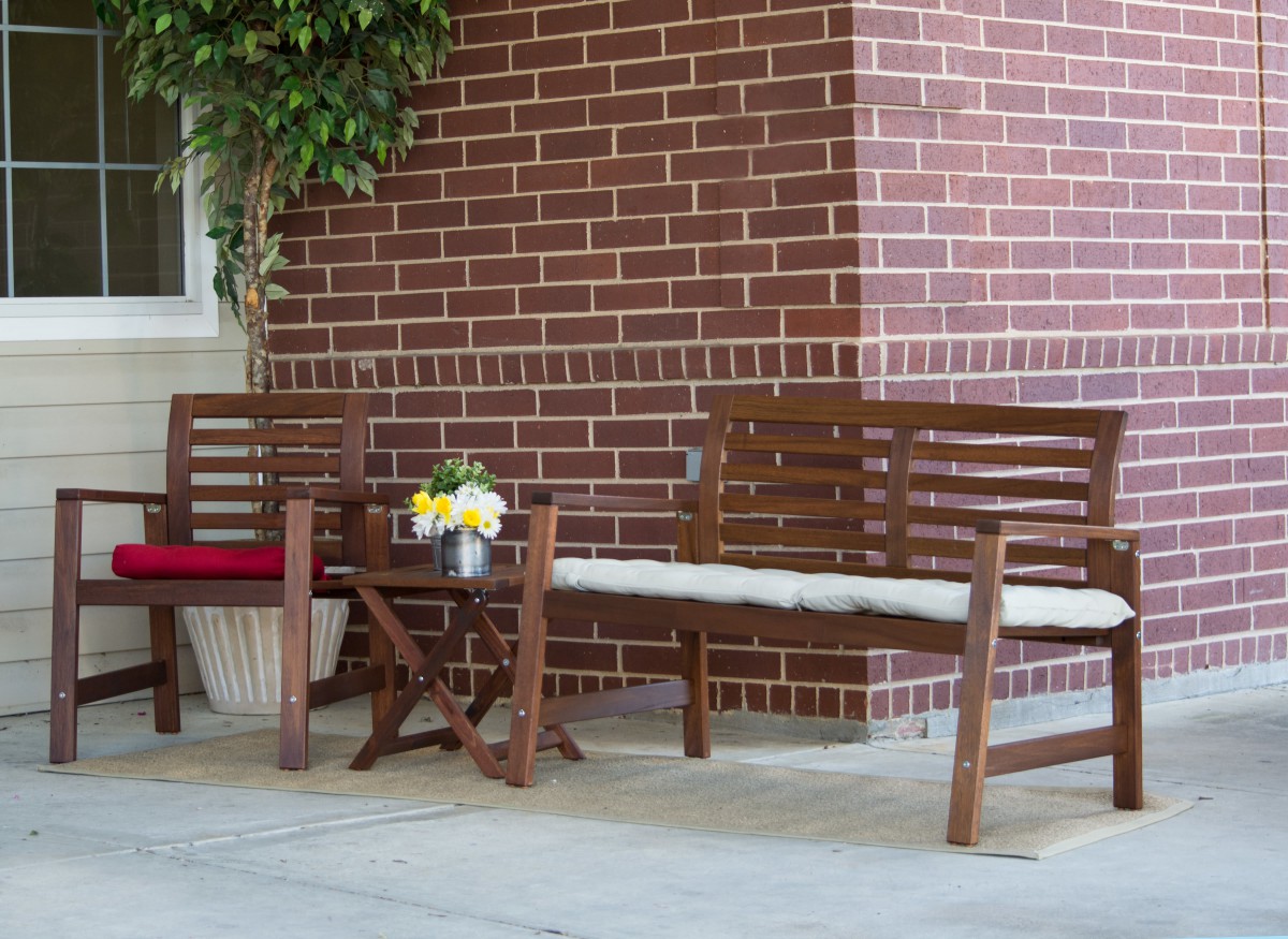 A cozy patio setup with wooden benches and a table against a brick wall.