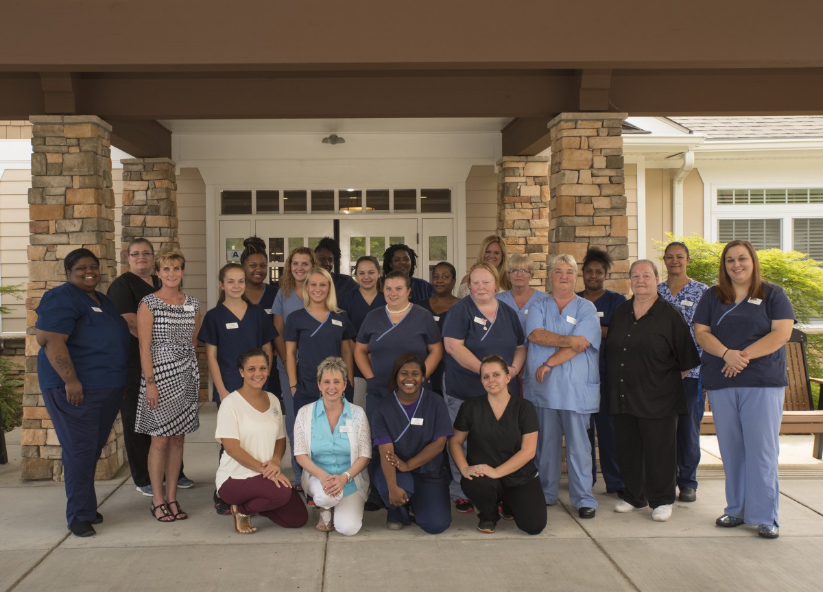 A diverse group of people in uniforms posing together outside a building.