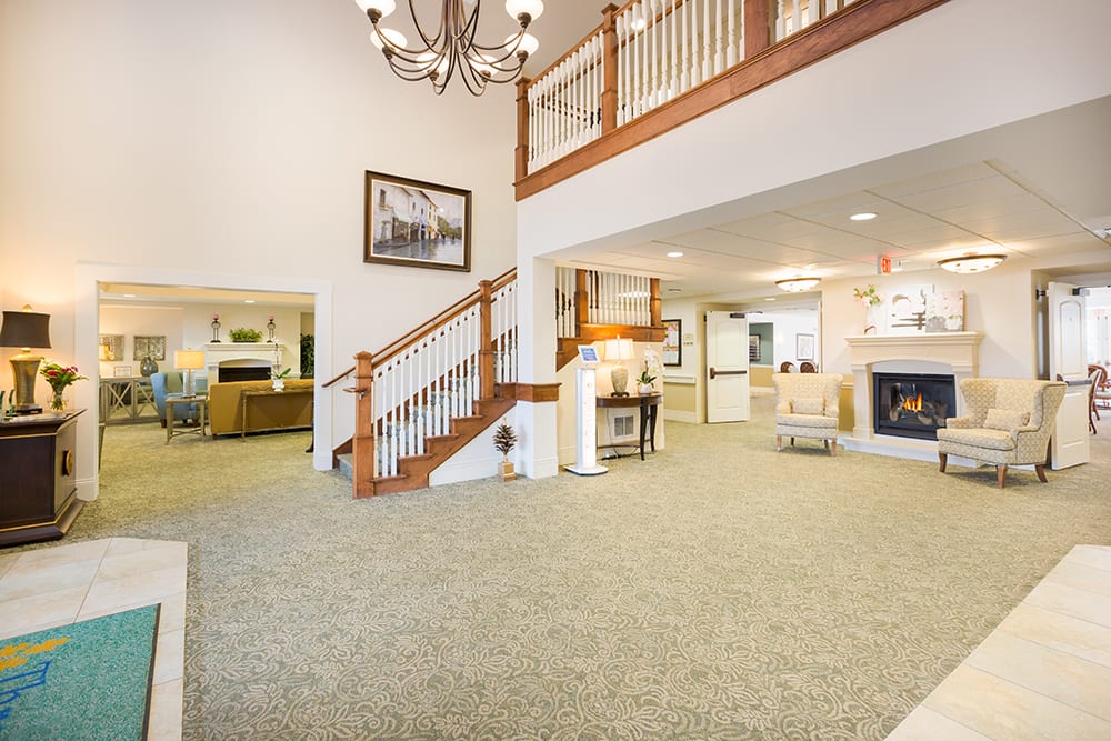 A spacious living room with a staircase, chandelier, and fireplace.