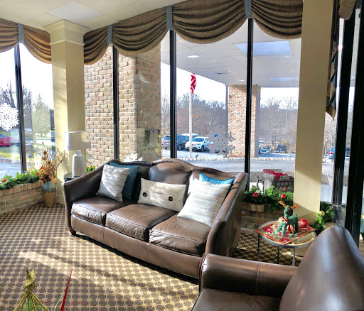 A cozy lounge area with a comfortable sofa, decorated with cushions and surrounded by large windows allowing natural light to fill the space.
