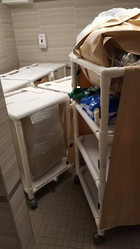 A cluttered storage area featuring plastic utility carts stacked with various items.