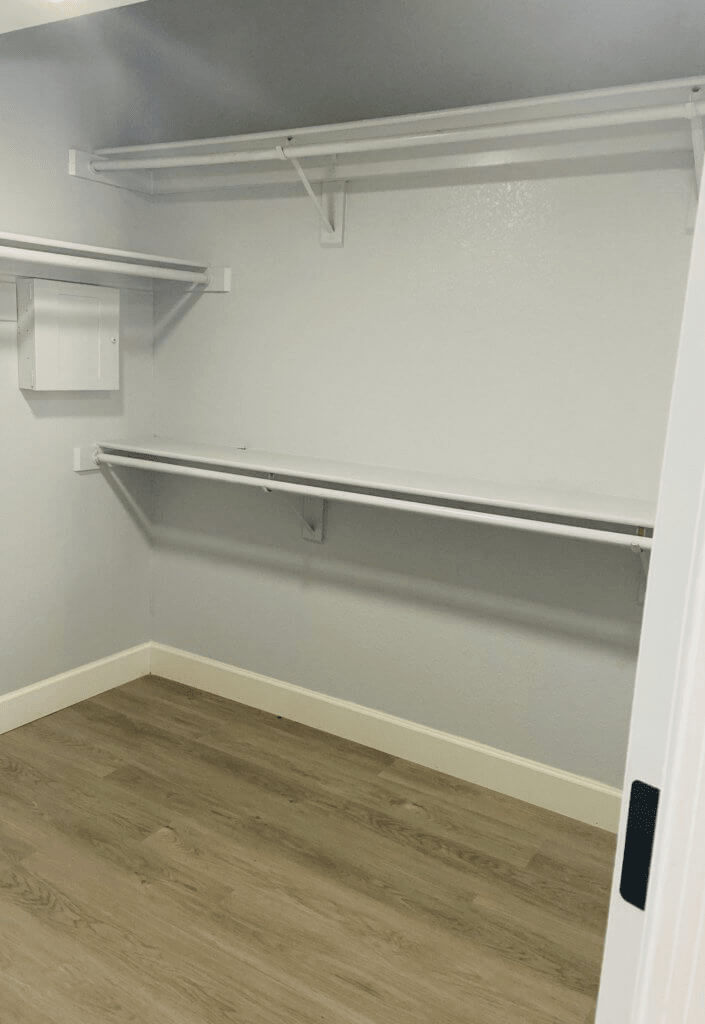 An empty closet with shelves and a wooden floor, ready for organization.