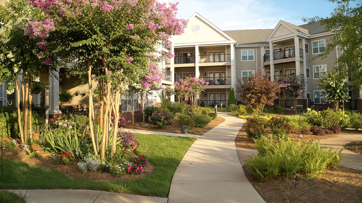 A scenic view of an apartment complex with landscaped gardens and blooming flowers.