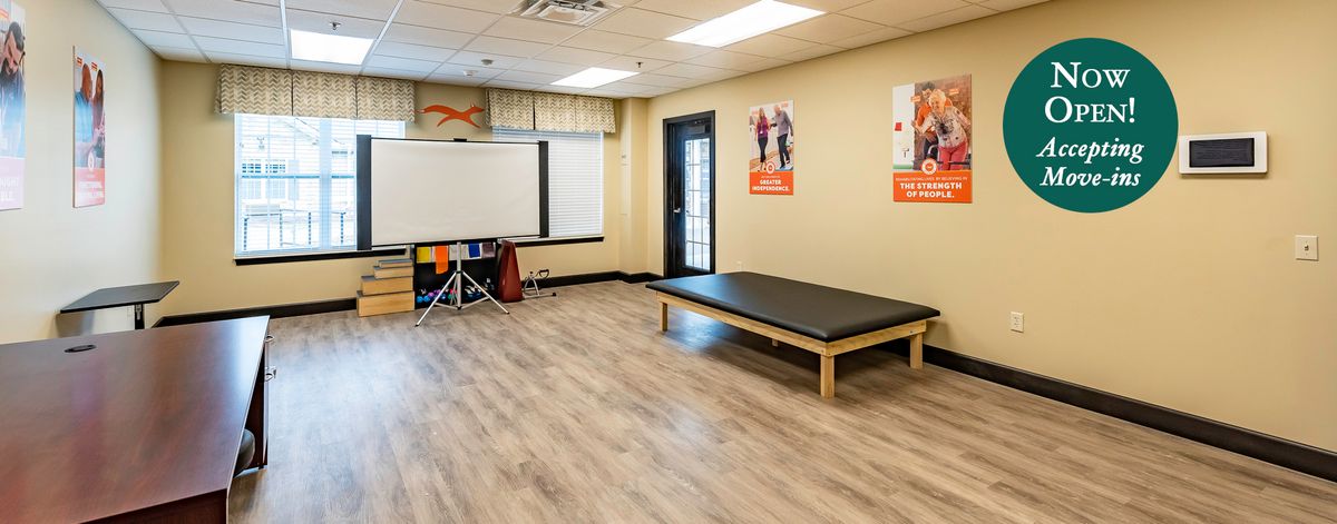 A well-lit physical therapy room with a therapy table and exercise equipment.