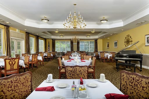 An elegant dining room with neatly arranged tables and chandeliers overhead.