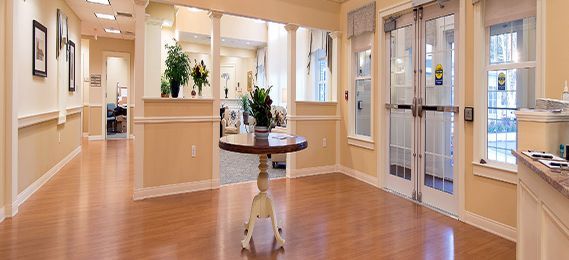 A welcoming entrance with a round table and plants on a wooden floor.