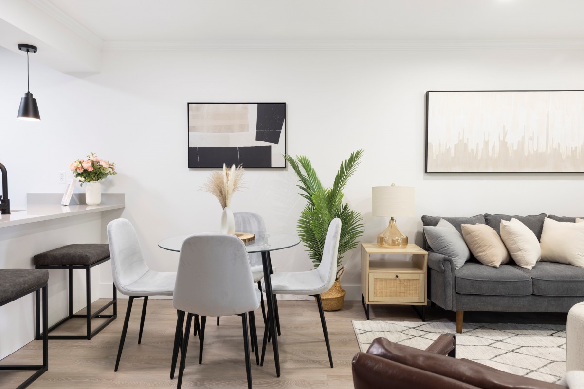 A modern and minimalist living room with a dining area featuring stylish furniture and greenery.