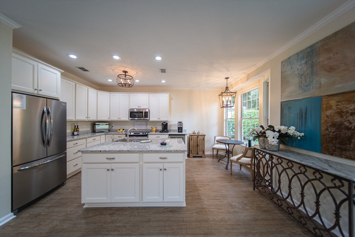 A modern kitchen with white cabinets, an island, and a cozy dining area.