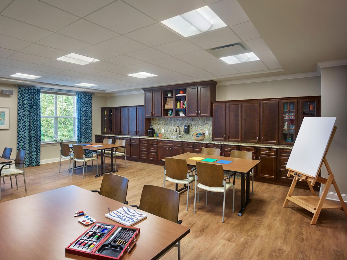A multipurpose room featuring kitchen appliances, tables and chairs arranged for a classroom setting.