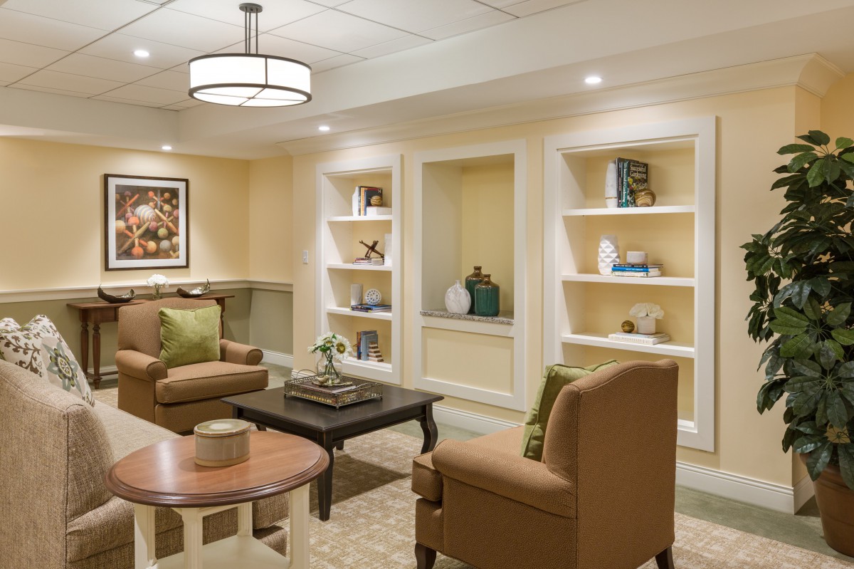 A cozy living room with comfortable seating, shelves displaying decor, and warm lighting.