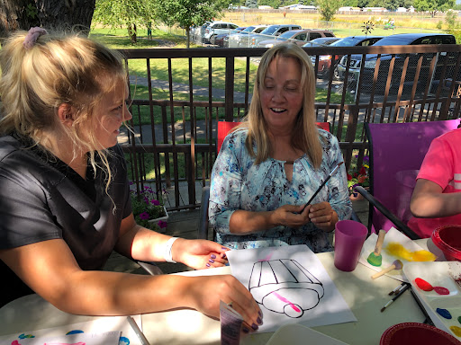 Two women enjoying a creative moment outdoors, working on art together.
