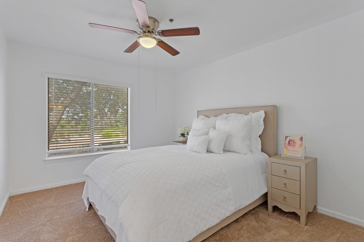 A cozy bedroom with a large bed, white bedding, and a ceiling fan.