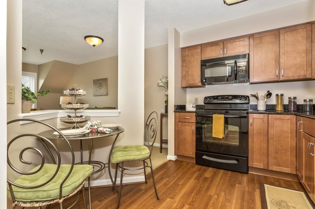 A modern kitchen with a small dining table set, featuring wooden floors and contemporary appliances.