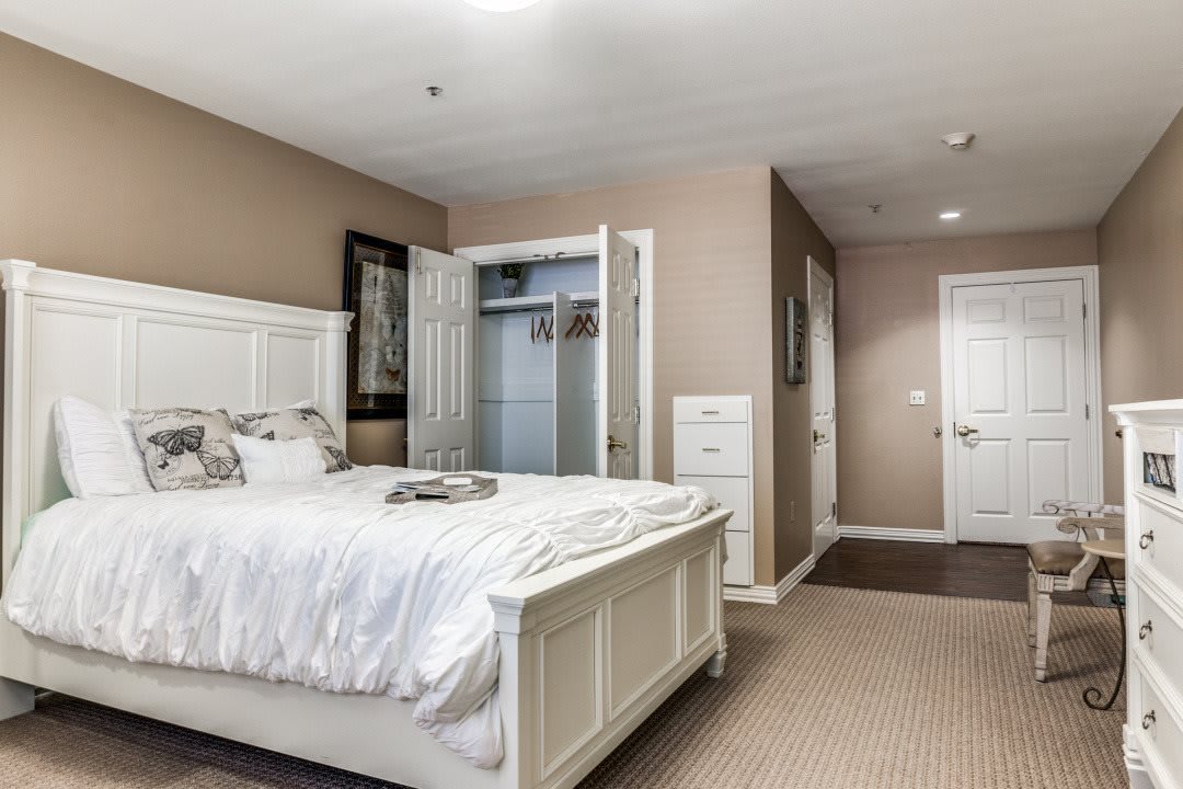 A bright and cozy bedroom with a white bed and an open closet.