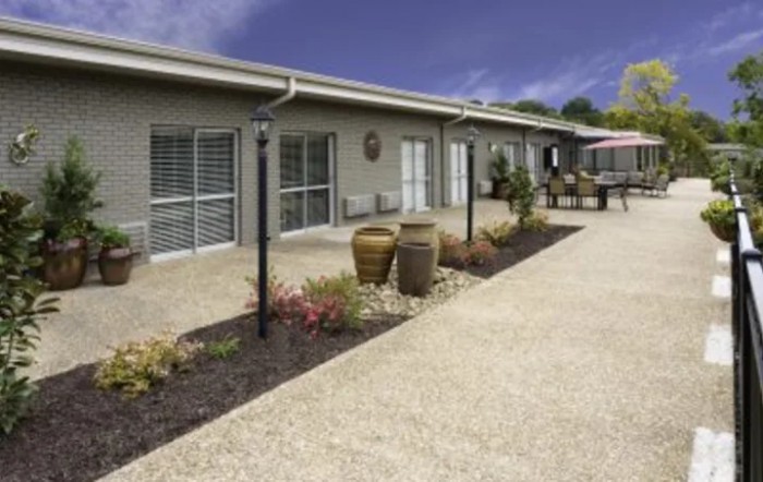 A modern building with a landscaped garden and paved walkway.