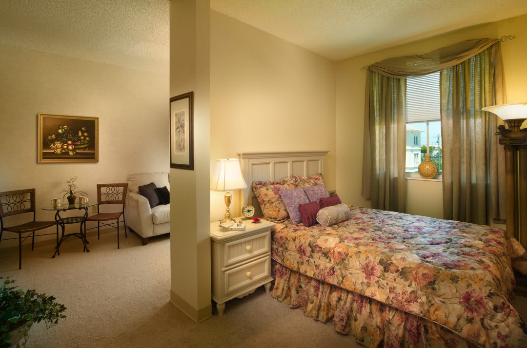 A cozy bedroom with floral bedding and a connecting living area.