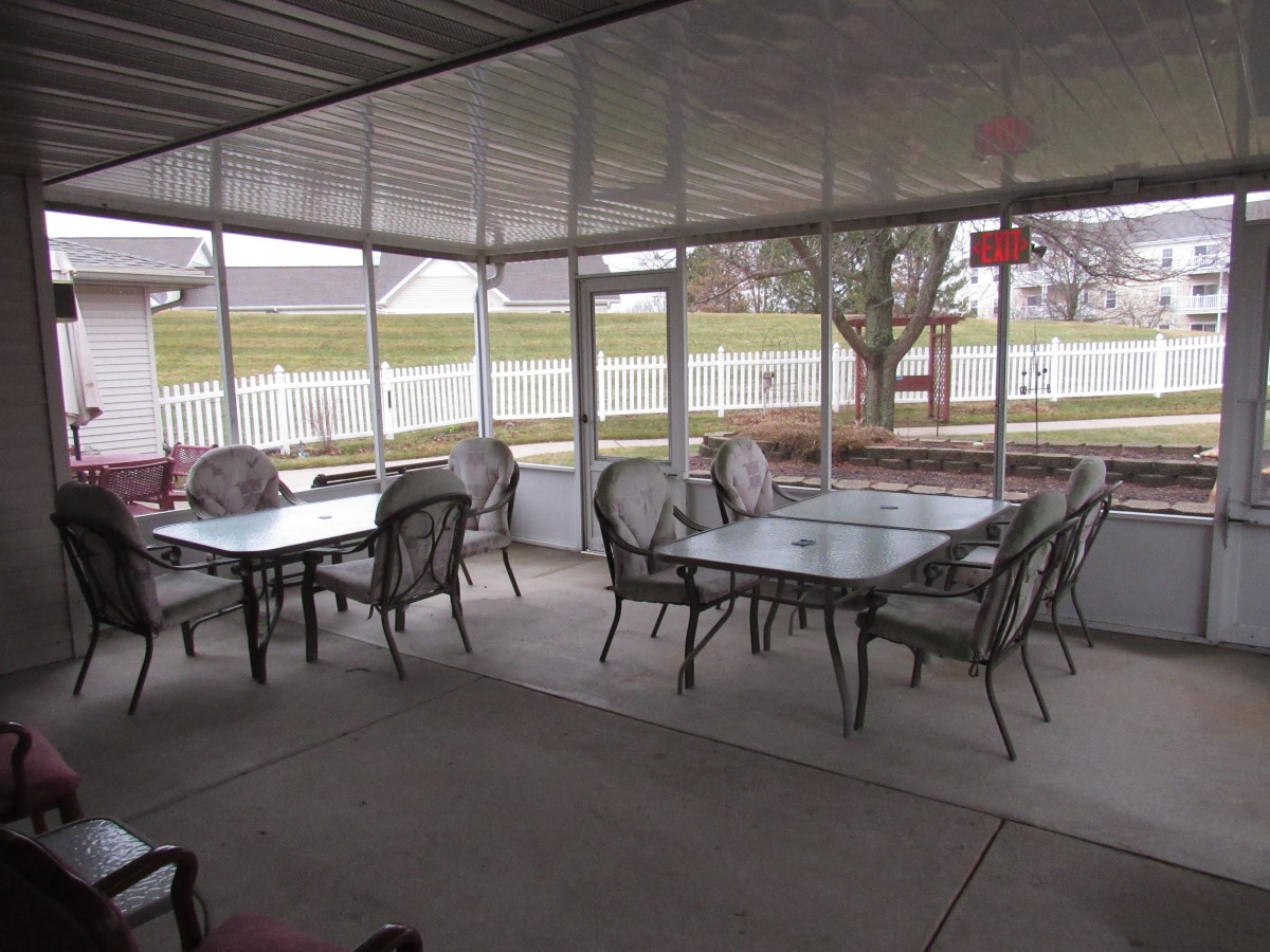 A covered outdoor patio with tables and chairs arranged for seating.