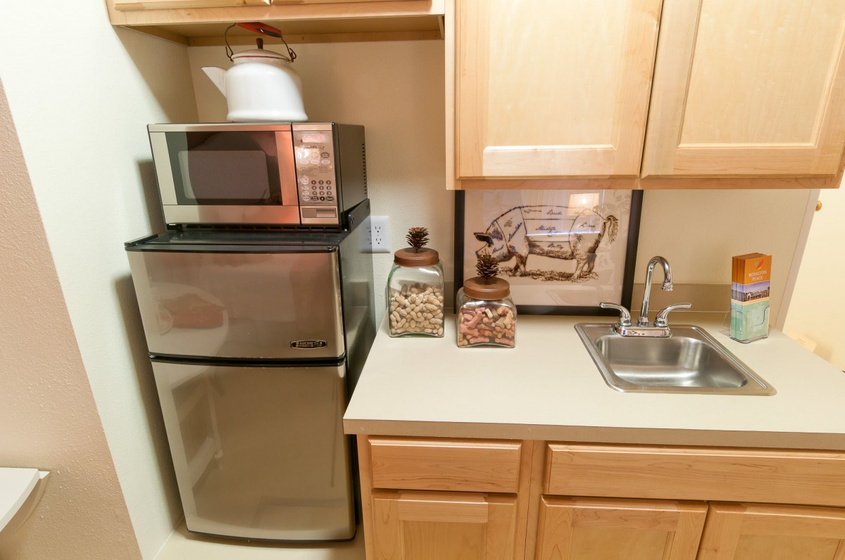 A compact kitchen setup featuring a microwave, mini fridge, and countertop with decorative containers.