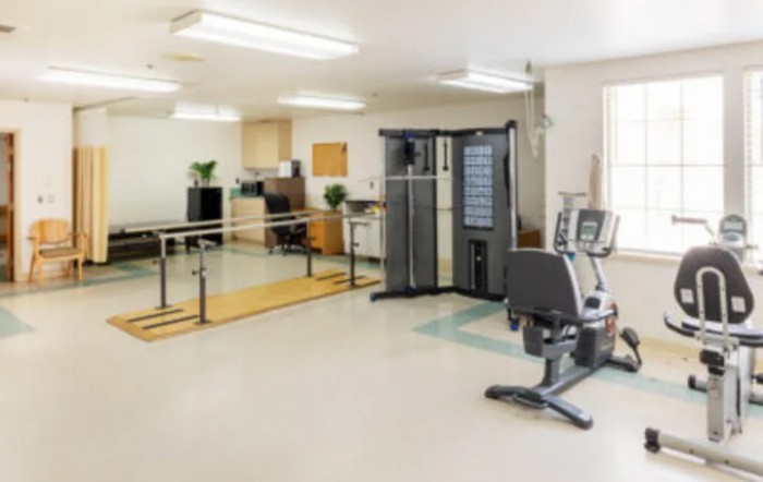 A fitness room with various exercise equipment and rehabilitation tools.