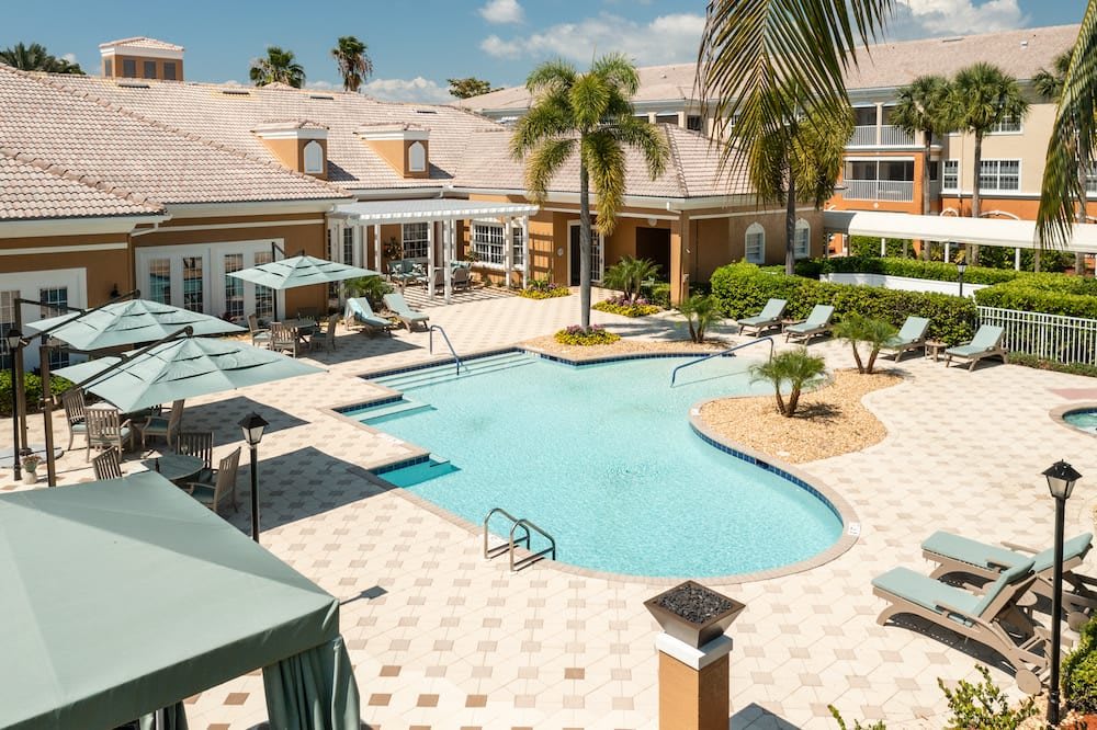 A luxurious hotel resort with an inviting swimming pool surrounded by palm trees and lounge chairs.